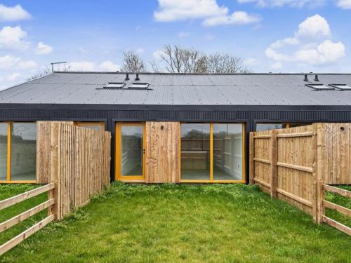 a house with a black roof and a wooden fence at Damson Barn in Bluntisham