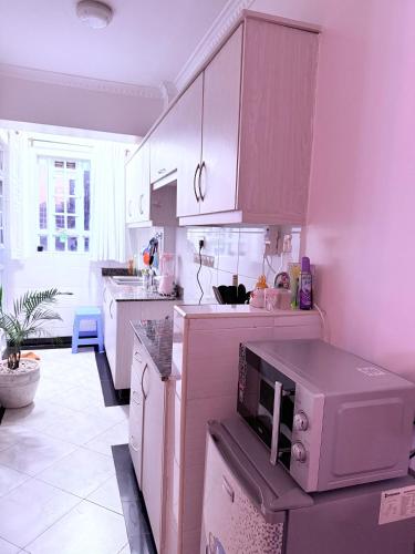 a kitchen with pink cabinets and a microwave at Beytumn Luxury Apartment - Ruiru in Nairobi