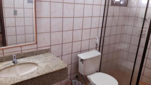 ein Badezimmer mit einem Waschbecken, einem WC und einem Spiegel in der Unterkunft Apart Hotel Praia do Pero in Cabo Frio