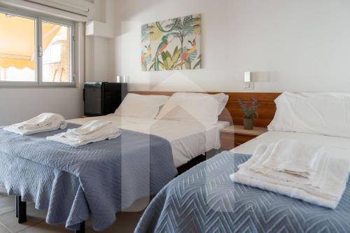 two beds in a hotel room with towels on them at Affittacamere Il Giardino in Alba Adriatica