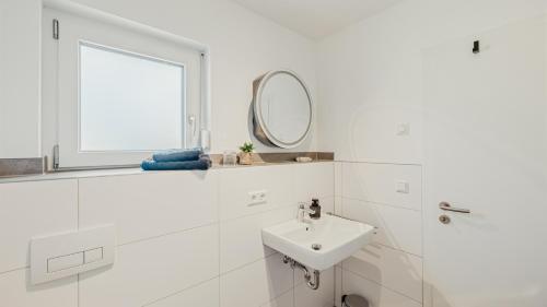 a white bathroom with a sink and a mirror at Apartment am Fuchseck in Schorndorf