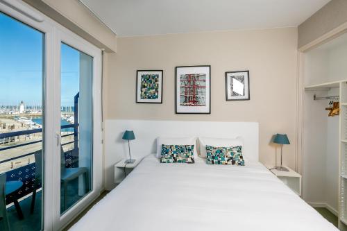 a bedroom with a large bed and a large window at Hôtel Port Haliguen in Quiberon