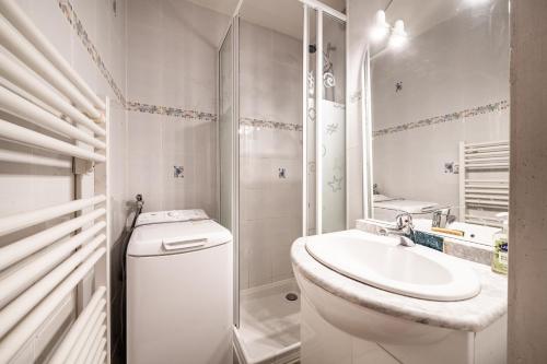 a white bathroom with a toilet and a sink at Entre Lac Et Montagne in Thollon