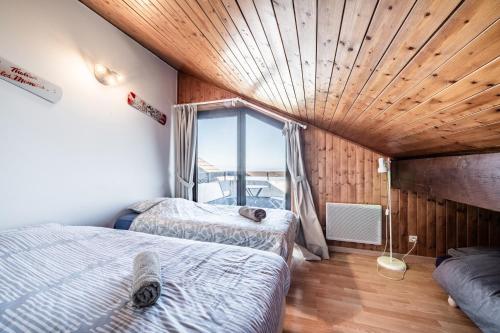 two beds in a room with a large window at Entre Lac Et Montagne in Thollon