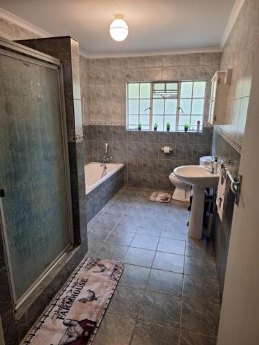 a bathroom with a shower and a tub and a sink at Guesthouse at Lucia in Bethlehem