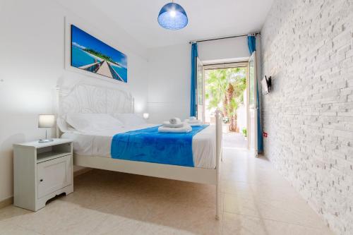 a white bedroom with a bed and a brick wall at Baia Verde - Sea Rooms in Baia Verde
