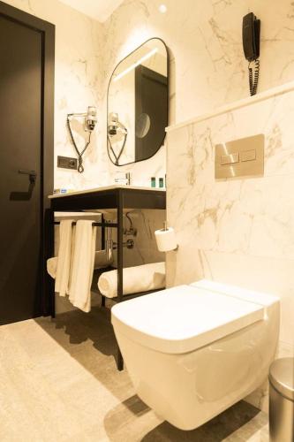 a bathroom with a toilet and a sink and a mirror at AZ Appart hotels Saitour in Mazagran