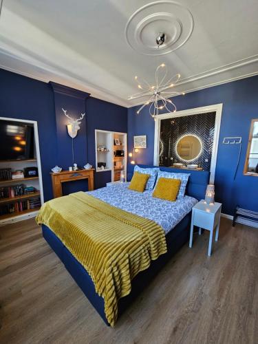 a blue bedroom with a king sized bed with yellow pillows at B&B van Zon aan Zee in Vlissingen