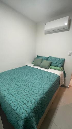 a bedroom with a bed with a green comforter at Full Studio in Stella Maris in Salvador