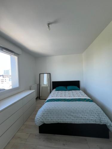 a white bedroom with a bed and a window at T2 cosy proche Versailles in Trappes