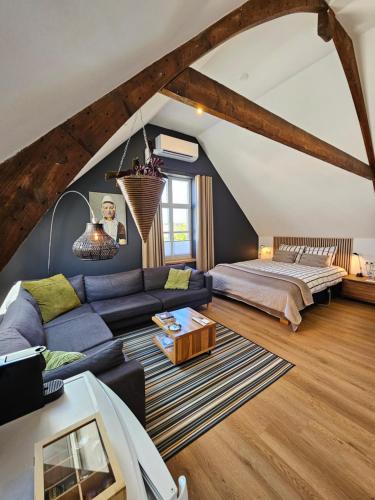 a living room with a blue couch and a bed at B&B van Zon aan Zee in Vlissingen
