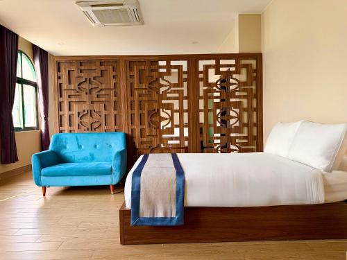 a bedroom with a bed and a blue chair at My Marina Beach Hotel Phu Quoc in Phú Quốc
