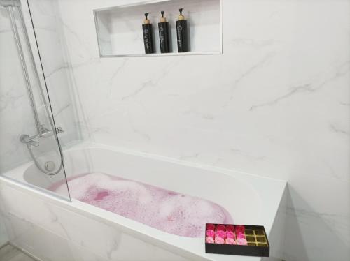 a white bathroom with a bath tub with pink dye at Marreiro's house Algarve - Child friendy - Private Pool in Lagos