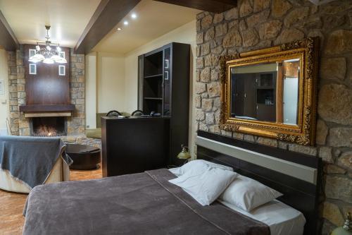a bedroom with a stone wall with a bed and a mirror at Nymfes Hotel in Kato Loutraki