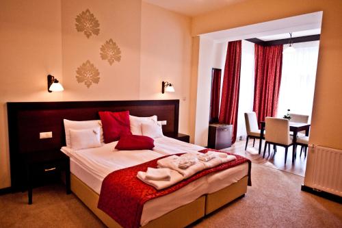a bedroom with a large bed and a dining room at Hotel Aurum in Hajdúszoboszló