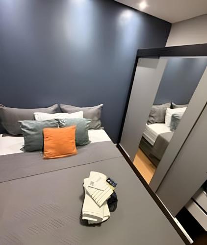 a room with a bed with an orange pillow and a mirror at Safiras Premium | Seu conforto em Cuiabá in Cuiabá