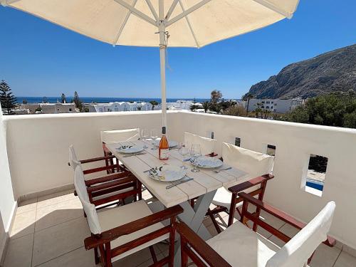 a table and chairs with an umbrella on a balcony at Villa Thea in Kamari