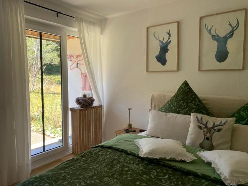 a bedroom with a bed with green sheets and deer heads on the wall at Schwarzwaldliebe in Schönwald