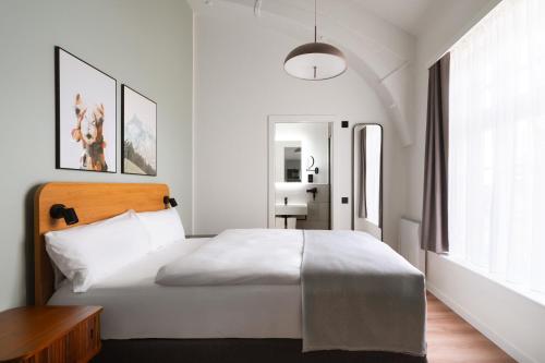 a white bedroom with a bed and a desk at Limehome London Streatham High Rd in London