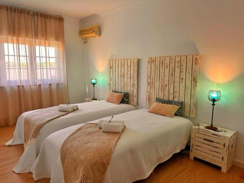 two beds in a bedroom with two lamps on a table at Sítio D'Elvas in Elvas