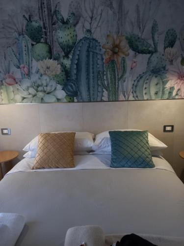 a bed with two pillows and a painting of cactus at Glamonia rooms in Campobasso