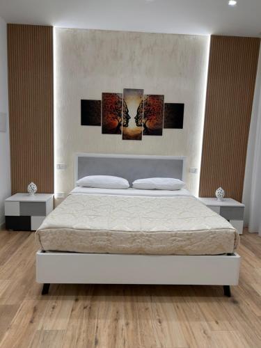 a bedroom with a white bed with four paintings on it at Marra Home B&B in Barletta
