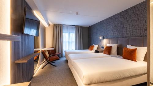 a hotel room with two beds and a window at Hotel Asteria in Venray