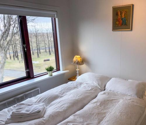 a white bed in a bedroom with a window at Fagrahlid Guesthouse in Hvolsvöllur
