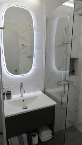 a bathroom with a sink and a shower with a mirror at Sandalis Hotel in Pythagoreio