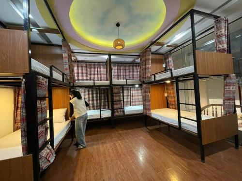 a person standing in a room with several bunk beds at Su Ha Giang Hostel in Ha Giang