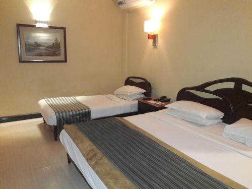 a hotel room with two beds and a table at Hotel Grand Peshawar in Peshawar
