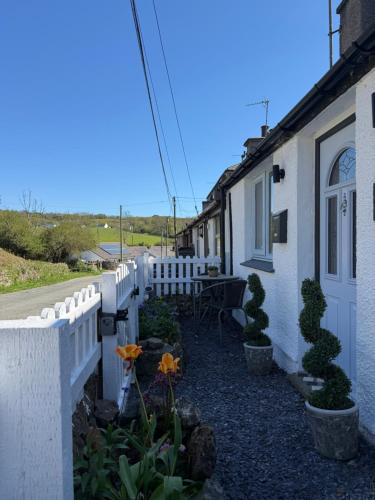 a white fence next to a house with flowers at Sandytoes Cottage in Pentraeth