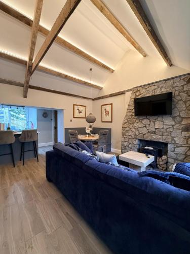 a living room with a blue couch and a stone fireplace at Sandytoes Cottage in Pentraeth