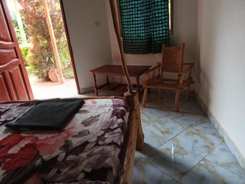 a bedroom with a bed and a table and a chair at Aunties Resort - Orutindo Kids Tantenlodge in Muhanga