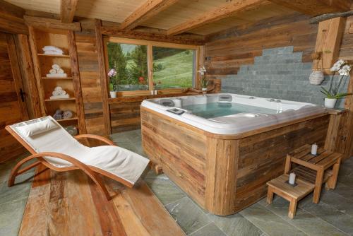 a jacuzzi tub in a wooden room with a chair at Au Bivouac de Napoléon et Spa in Bourg-Saint-Pierre