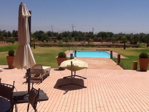 a patio with a umbrella and chairs and a pool at DOMAINE VILLa in Tameslouht