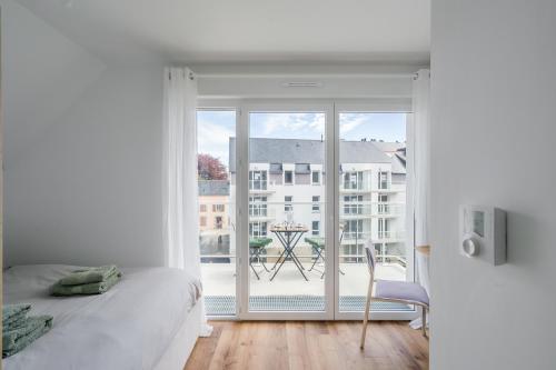 a bedroom with a bed and a view of a balcony at Studio de la Plage des Dames - À 50 m de la plage in Douarnenez