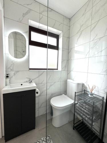 a bathroom with a toilet and a sink and a window at Inisfail in Killarney