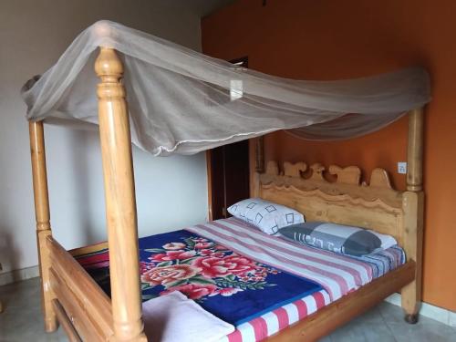 a bedroom with a wooden bed with a canopy at Aunties Resort - Orutindo Kids Tantenlodge in Muhanga