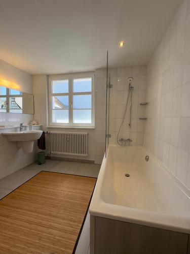 a white bathroom with a tub and a sink at Maison Bleue Dreiländereck, Design Apartment mit Terrasse in historischem Landhaus nahe Basel in Kandern