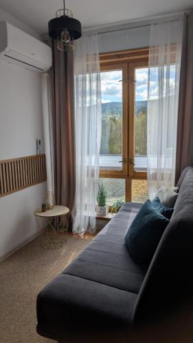 a bedroom with a couch and a large window at Domek za rzeką in Zawoja