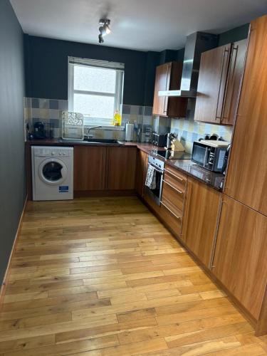 a kitchen with wooden cabinets and a wooden floor at Metro 8 Inverness City Centre in Inverness