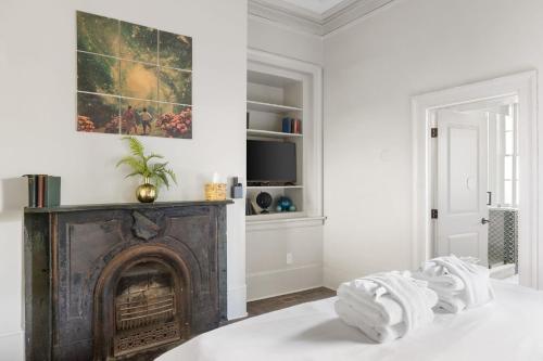 a white room with a fireplace and towels on a bed at King Suite 2nd FloorHotel Boutique in Savannah