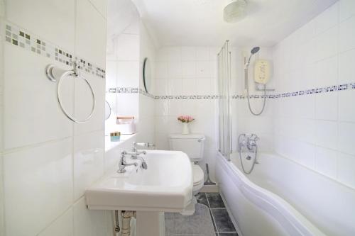 a bathroom with a sink and a tub and a toilet at Lavender Cottage in Gillingham