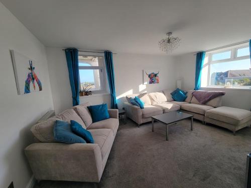 a living room with two couches and a table at Cwtch y Môr - NEW Outdoor Pool Spacious 3 bed, sea & mountain views in Holy Island