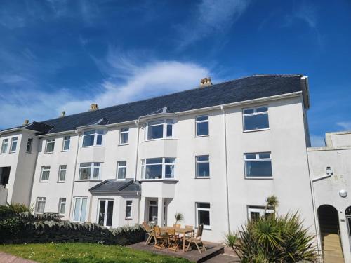 a large white building with a table in front of it at Cwtch y Môr - NEW Outdoor Pool Spacious 3 bed, sea & mountain views in Holy Island