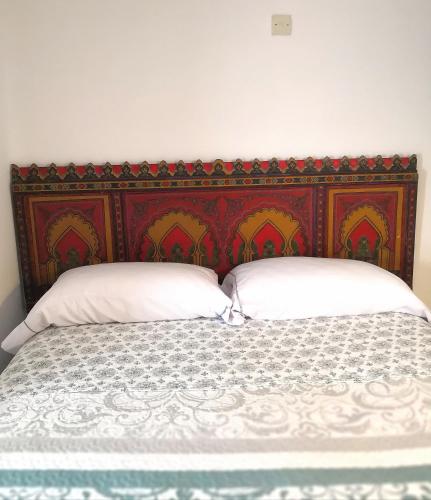 a bed with a red headboard and two white pillows at Riad la madriguera de Tetuan in Tétouan