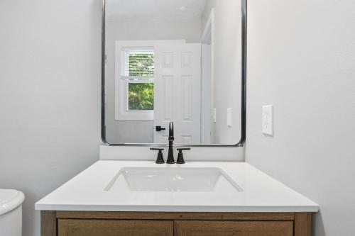 a white bathroom with a sink and a mirror at Elegant Modern Ranch Home in Atlanta
