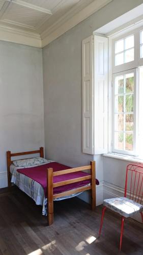 a bedroom with a bed and a chair and a window at Vila Santa Eulália Hostel in Pelotas