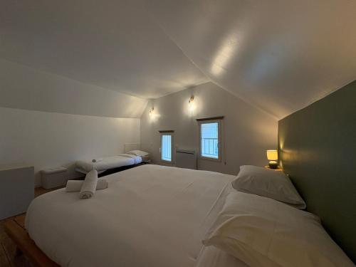 a white bedroom with two beds and two windows at Clécy Chouette maison atypique centre in Clécy